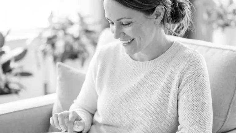 Smiling woman using tablet while sitting on couch
