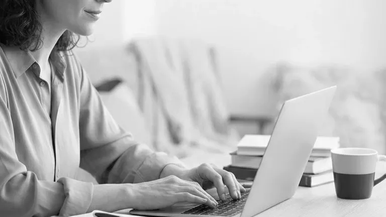 Person typing on laptop at desk with coffee
