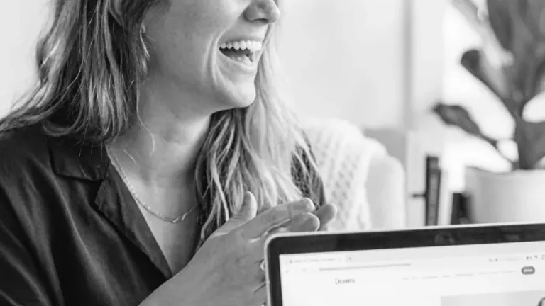 Woman smiling while working on laptop indoors